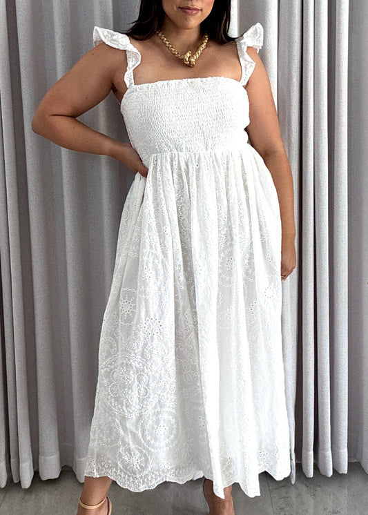 Woman in a white dress standing in front of a white curtain